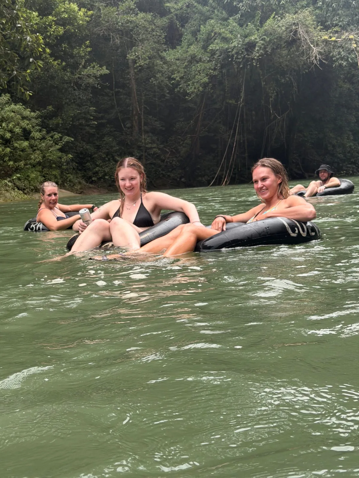 Turistas haciendo tubing en un río de aguas verdes rodeado de selva en Lanquín, Guatemala