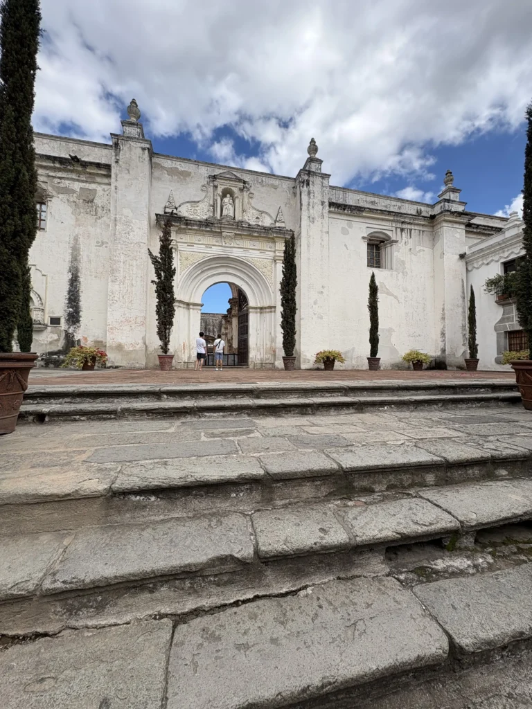Escalinata y arco colonial rodeados de cipreses en Antigua Guatemala