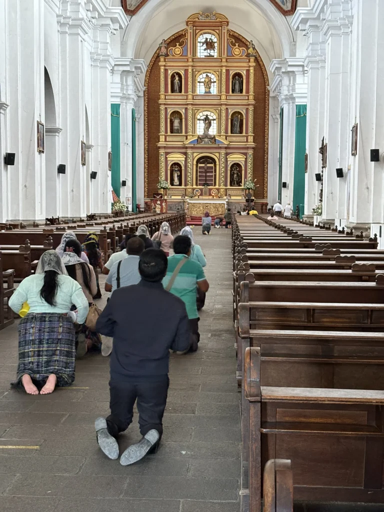 Nave y altar dorado de la Iglesia de San Francisco el Grande con fieles en oración