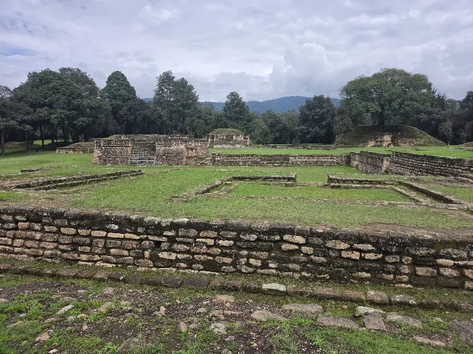 Plazas y estructuras de piedra de Iximché con montañas al fondo, Tecpán