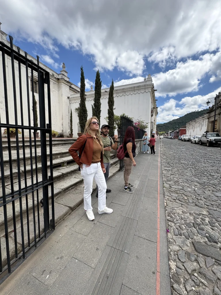 Viajera junto a una reja y muros coloniales en una calle de Antigua Guatemala