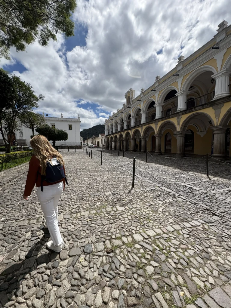 Viajera caminando junto a los portales del Parque Central de Antigua Guatemala